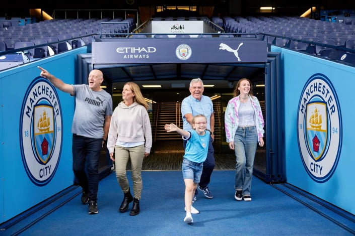 A family of five walks through the tunnel at Etihad Stadium onto the pitch during the Etihad Stadium tour.