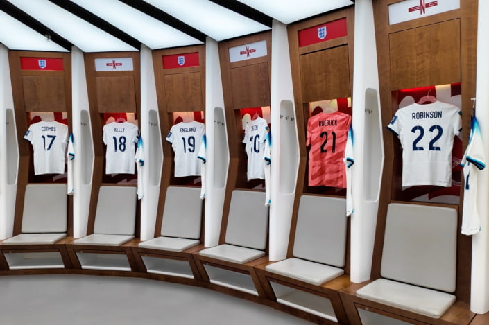 Home dressing room at wembley stadium showing famous shirts and the seating area.